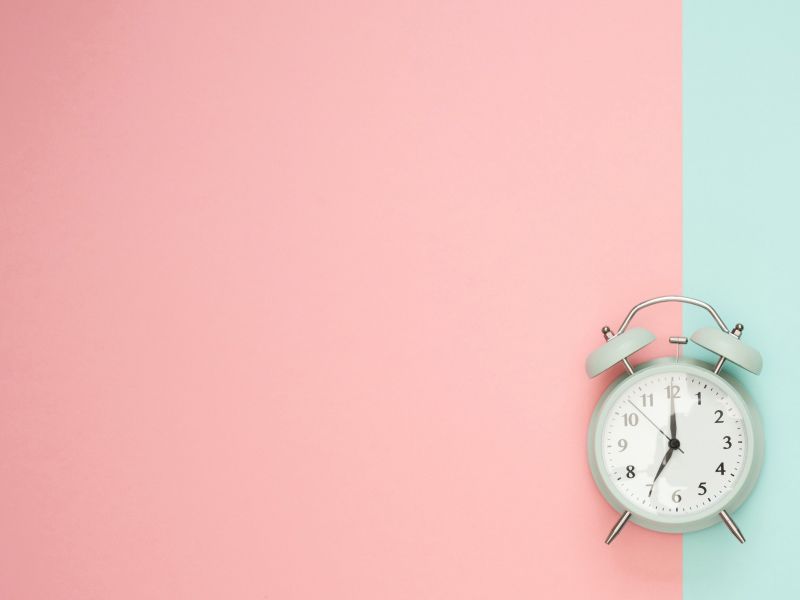 Mint colored alarm clock on a peach and mint colored background