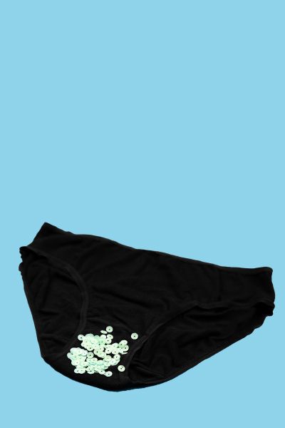 Black underwear with glitter sprinkled on them with a light blue background
