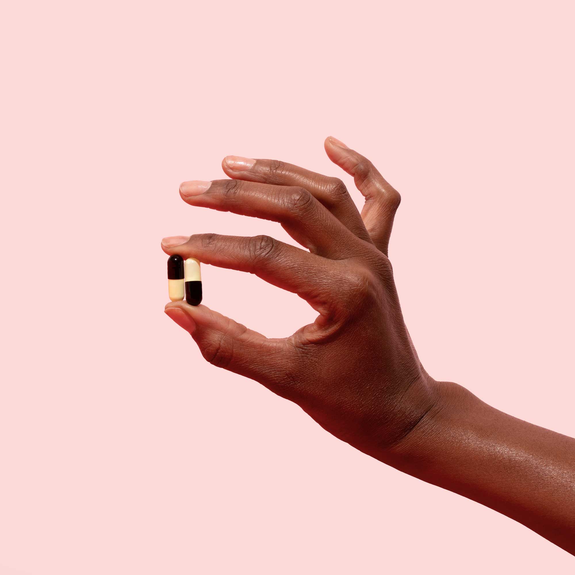 Woman's hand holding UTI antibiotics on a pink background