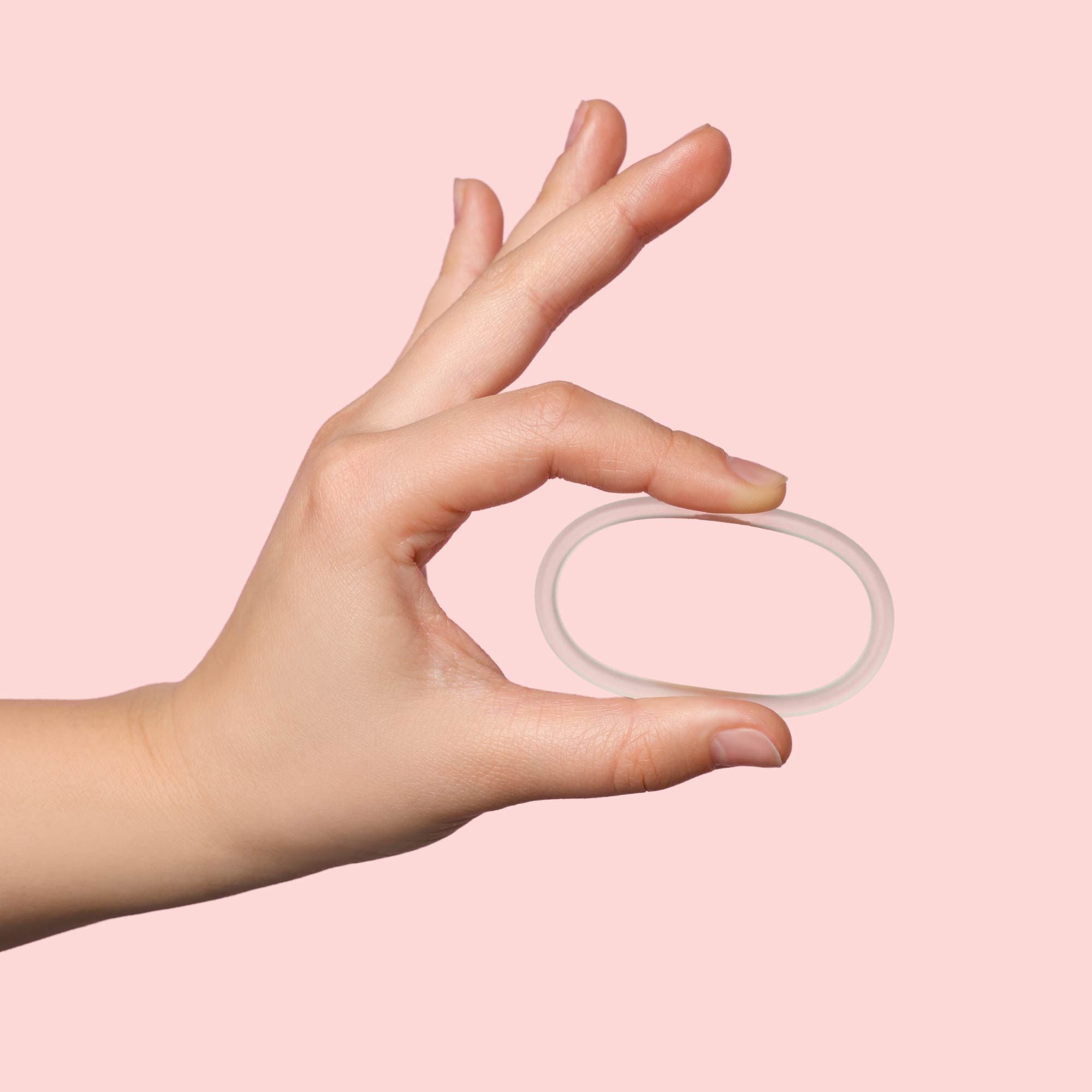 Woman's hand holding NuvaRing Birth Control with a pink background
