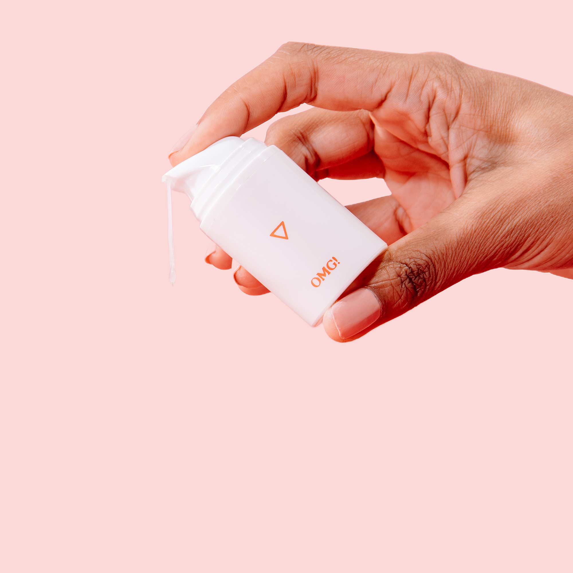 Woman's hand squeezes bottle of Wisp OMG! Cream while cream drips out on a pink background
