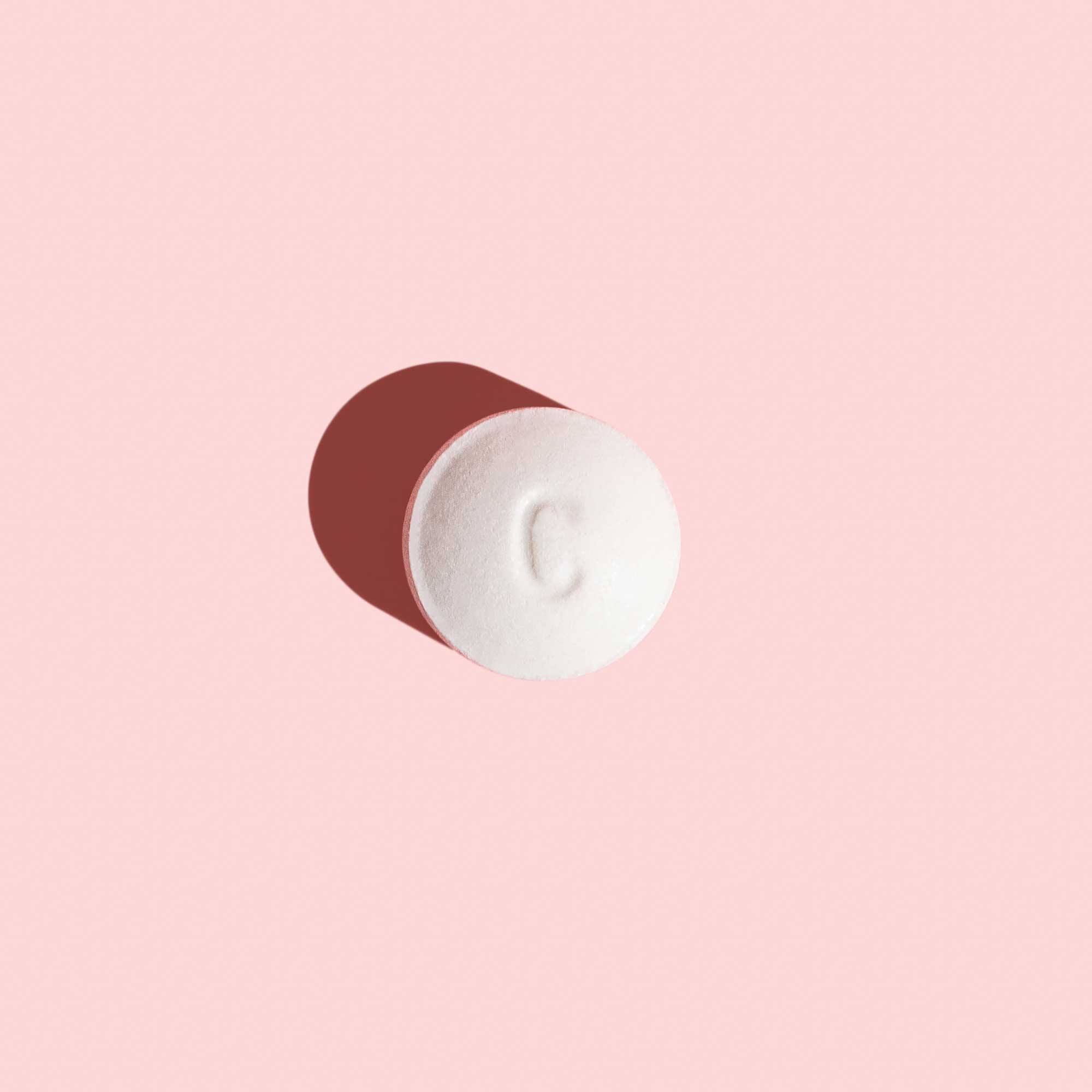 A Plan B pill on a pink surface
