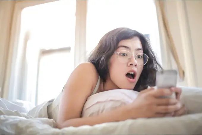 Girl looking at her phone with a shocked expression on her face