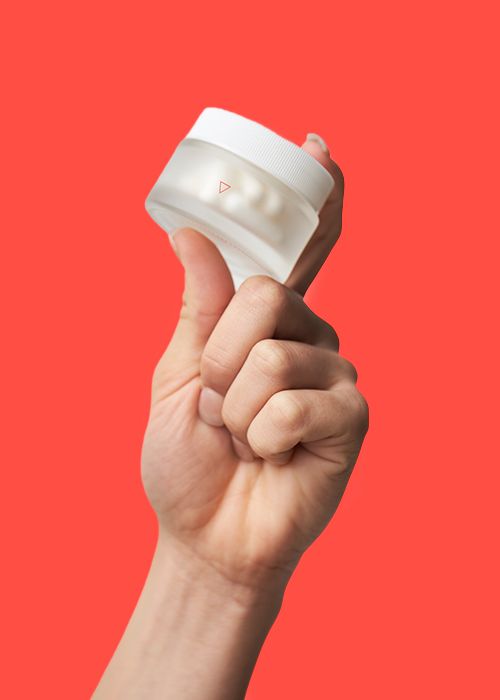 woman's hand holding glass jar of boric acid suppositories against red background