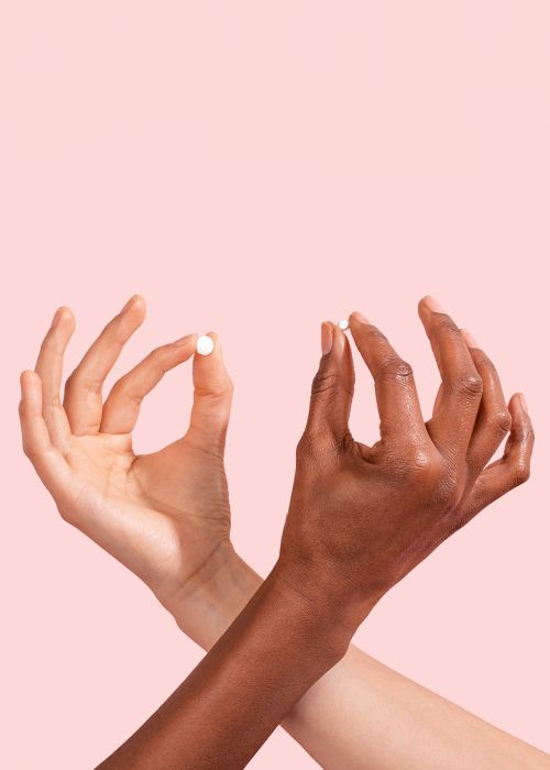 Hands holding Plan B and Ella pills on a pink background