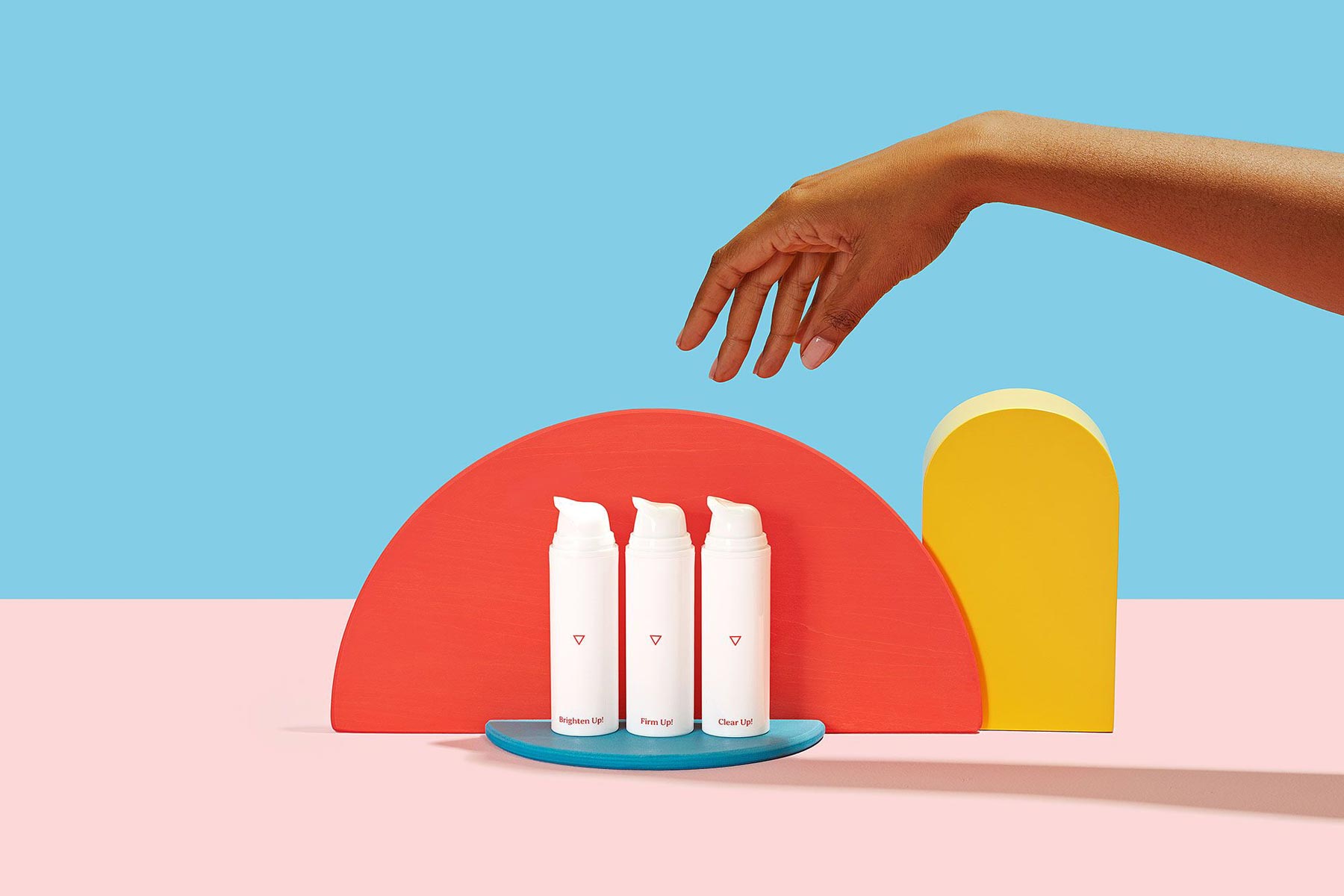 woman's hand reaching for Wisp skincare products on a colorful geometric background