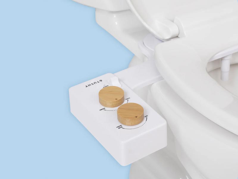 Tushy Bidet connected to a toilet with a light blue background