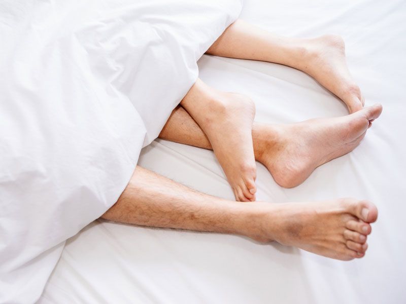 Couples feet wrapped in white bedding