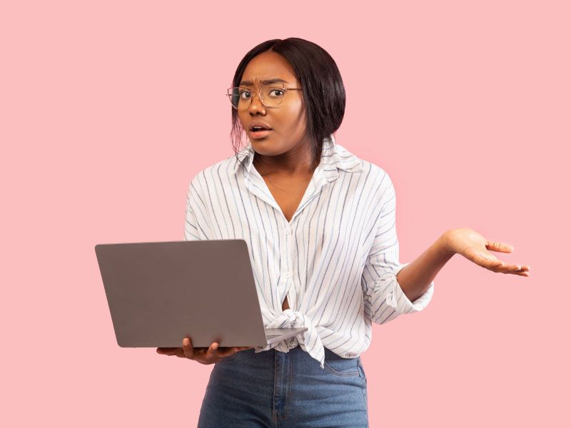 Female holding a laptop and looking confused with a pink background