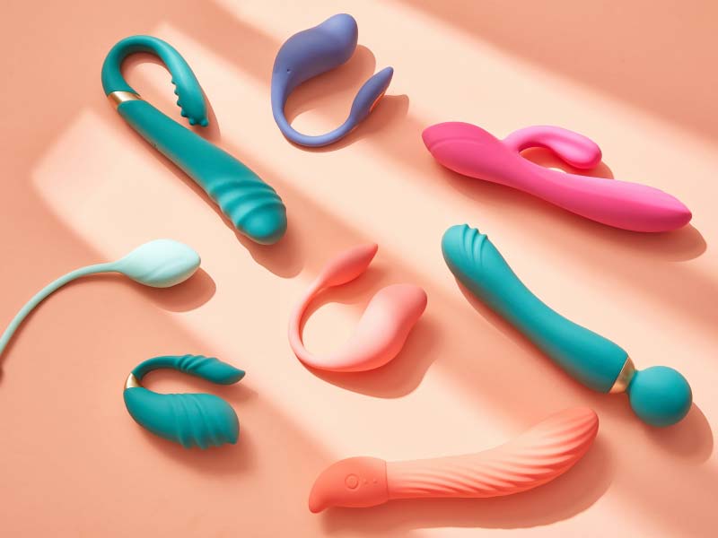 Multiple colorful sex toys on a peach colored surface