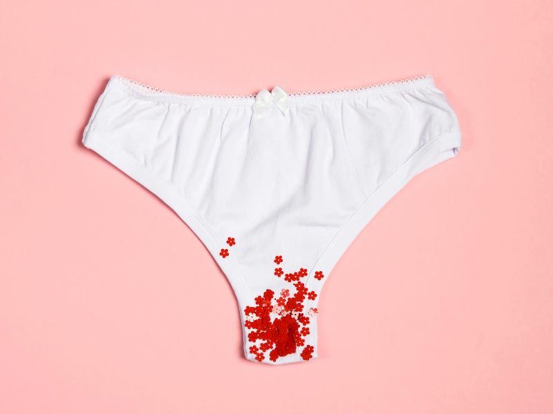 A pair of white underwear with red glitter indicating menstruation on a pink background