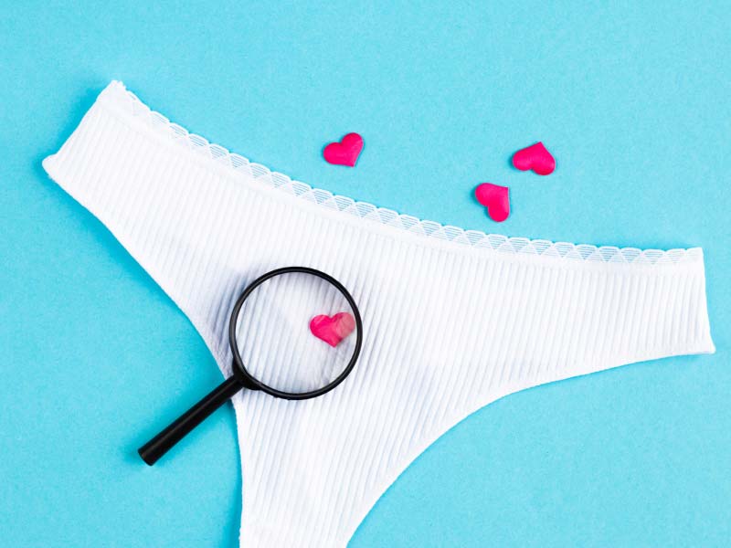 A pair of white underwear with a magnifying glass on them over a light blue surface