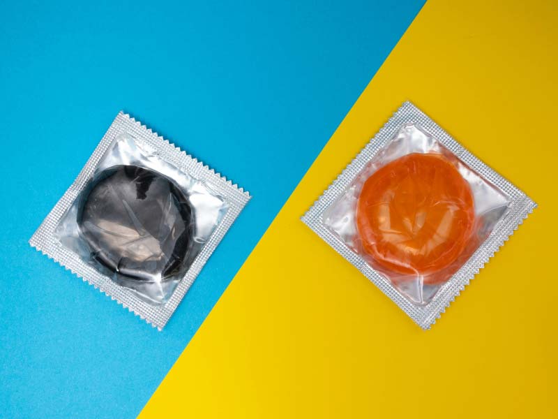 A purple and and orange condom on a blue and yellow surface