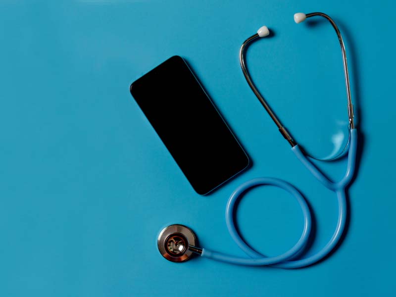 A stethoscope and a mobile phone laying on a teal surface