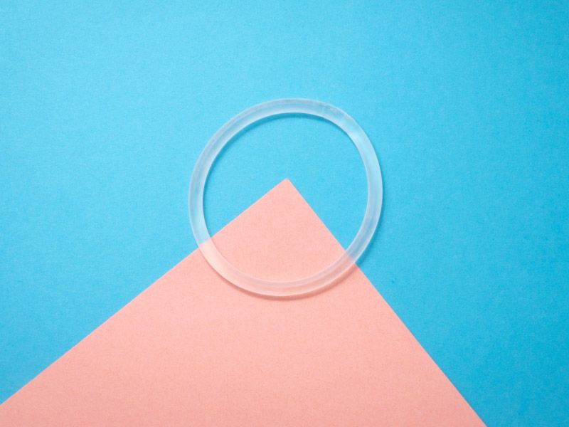 Nuvaring the vaginal birth control ring sitting on a pink and blue geometric background