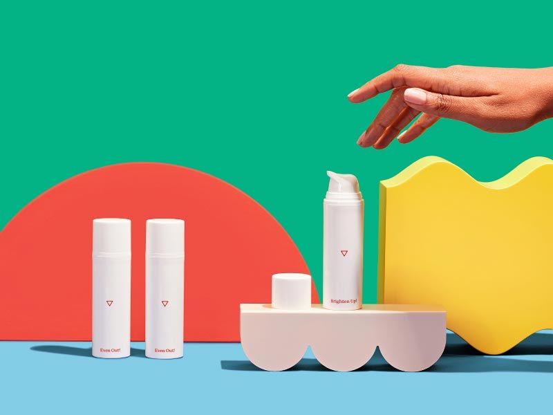 3 Wisp Skincare bottles with a person's hand reaching for them with colorful abstract shapes and a green and light blue background