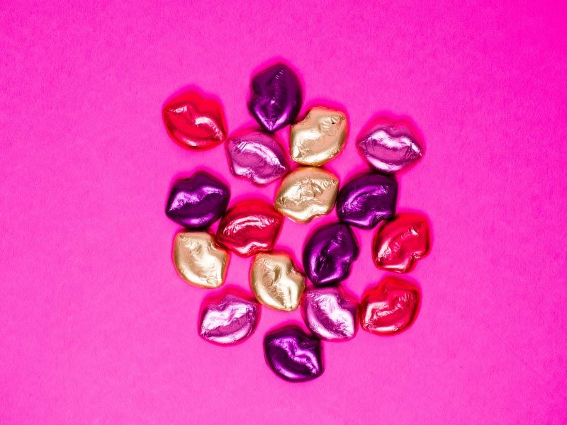 Multi-colored candy kisses on a fuchsia-colored surface