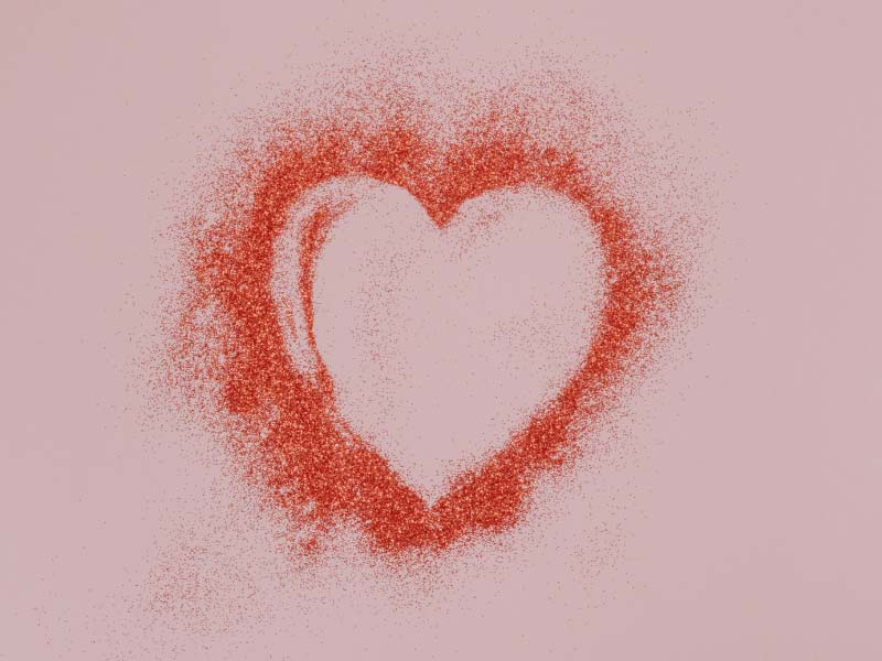 A heart formed with red powder on a pinkish-purple surface
