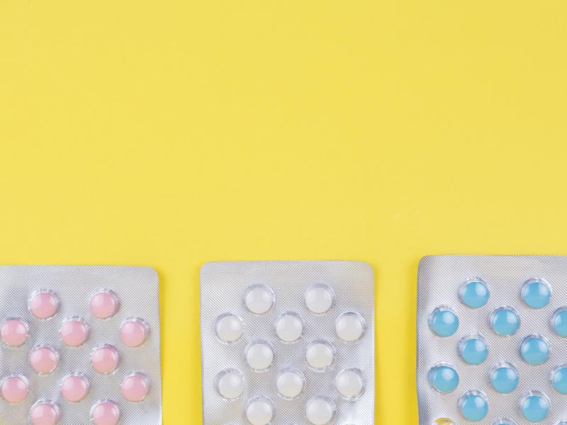 3 packets of colorful pills on a yellow background