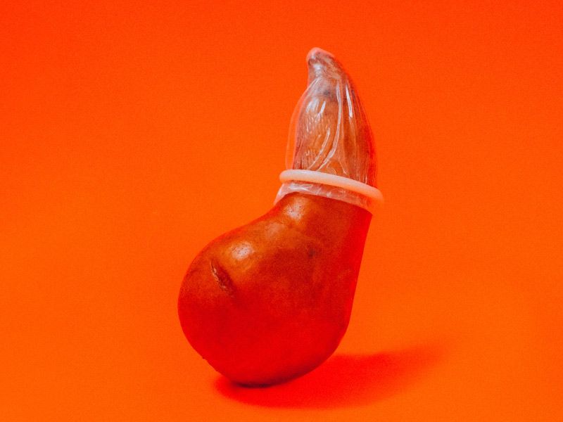 a red fruit wearing a condom on an orange background