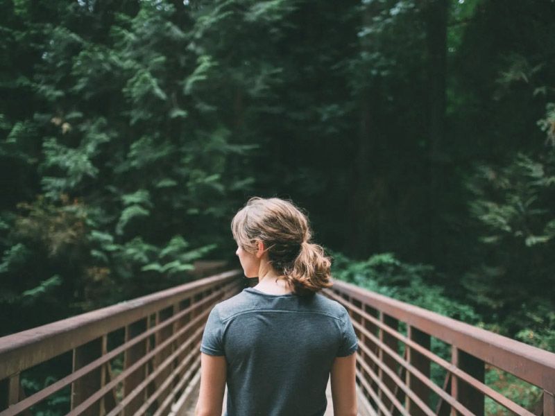 a woman standing on a bridge in a forest