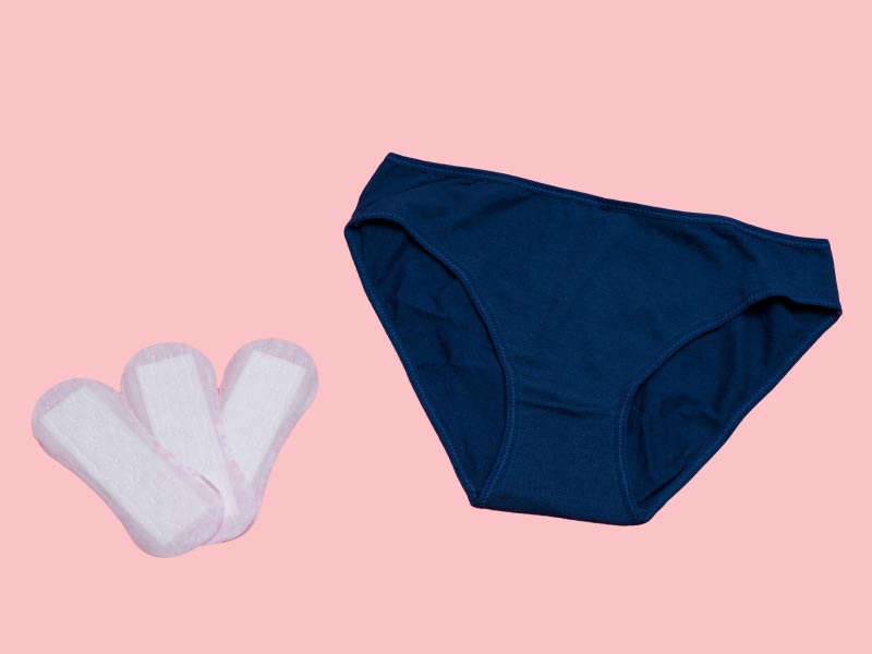 Dark blue underwear and 3 menstrual pads on a pink background