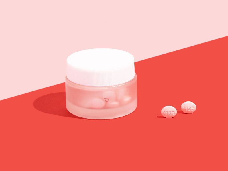 Wisp glass jar on pink and red surface with two pills outside the bottle