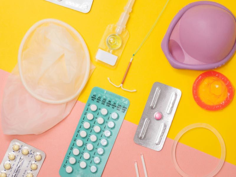 Multiple types of contraceptives on a yellow and pink background