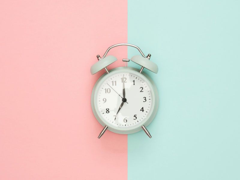 Mint colored alarm clock on a peach and mint colored background