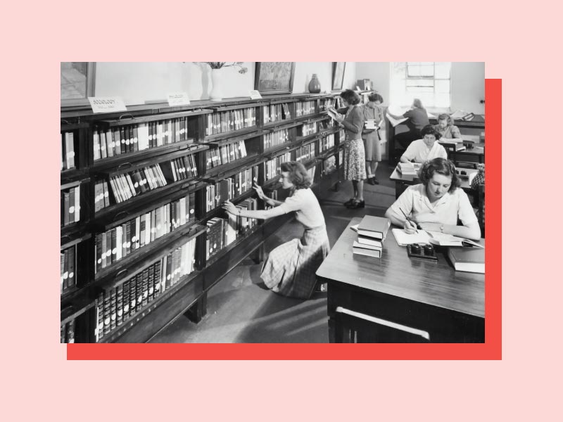 A black and white image of women studying in a library