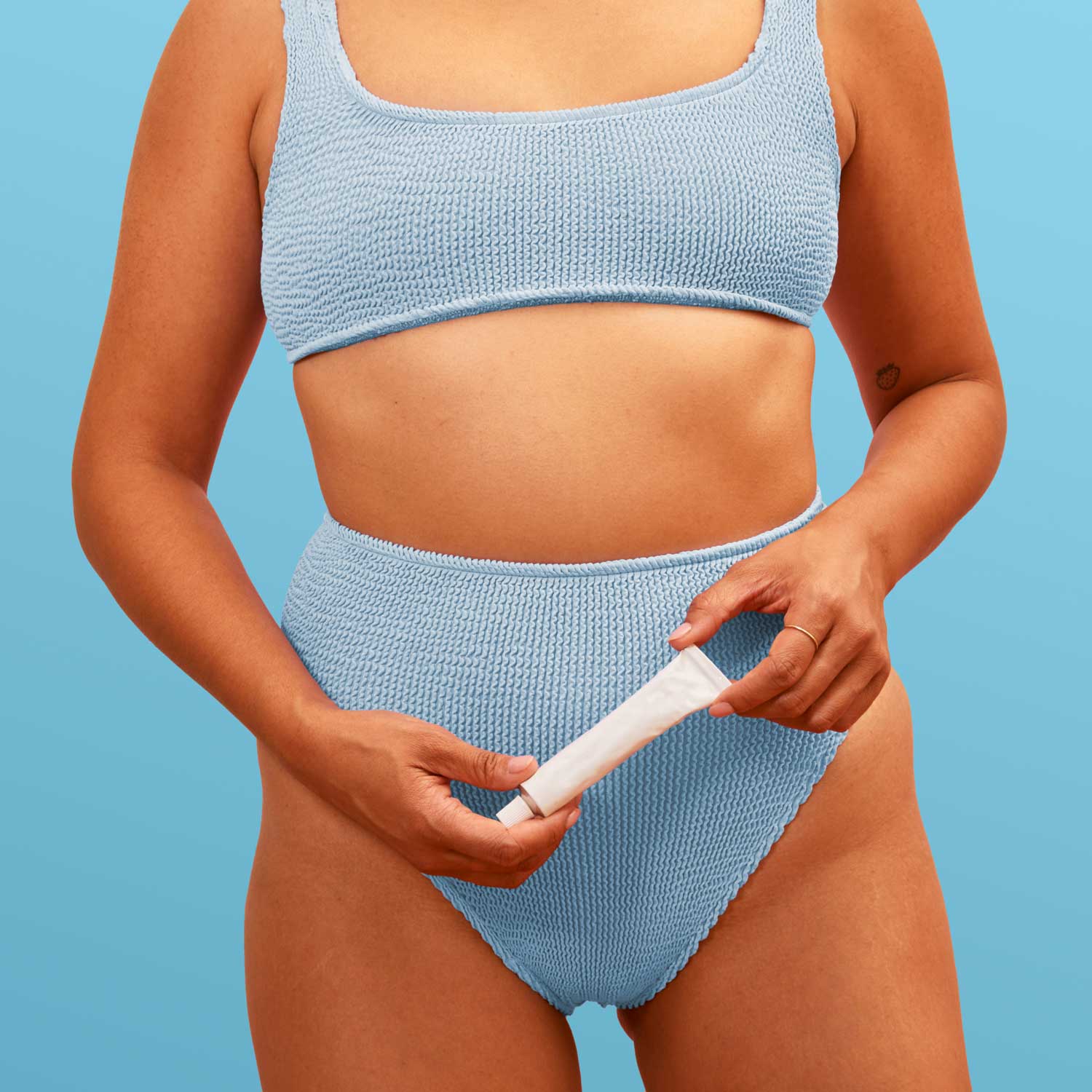 Model holding a tube of Wisp Estradiol Vaginal Cream with a blue background