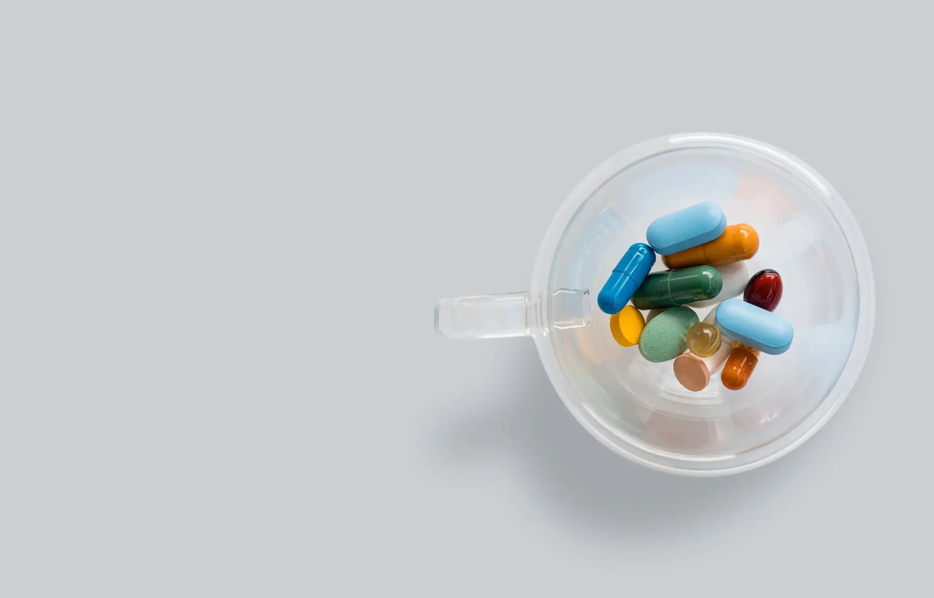 various pills in a glass cup on a white background