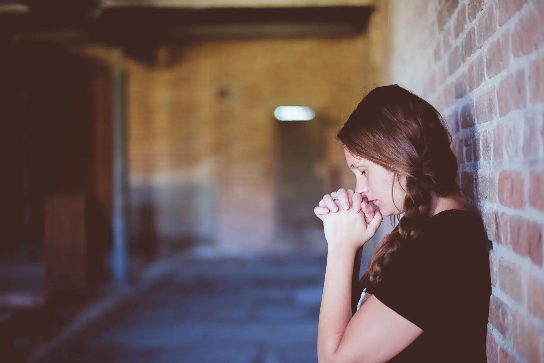 upset woman leaning against a brick wall