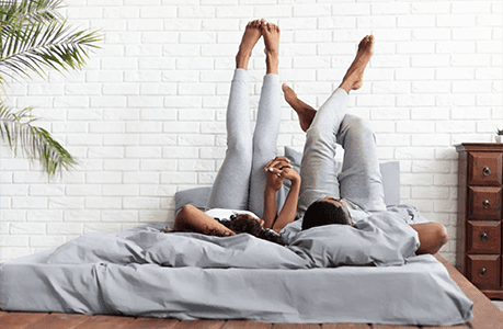 Man and woman holding hands while laying in bed