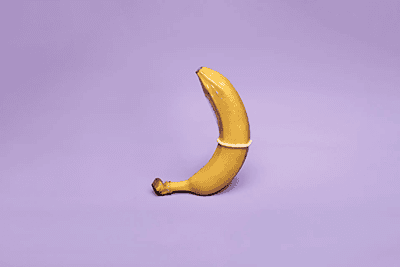 Banana wearing a condom on a purple background