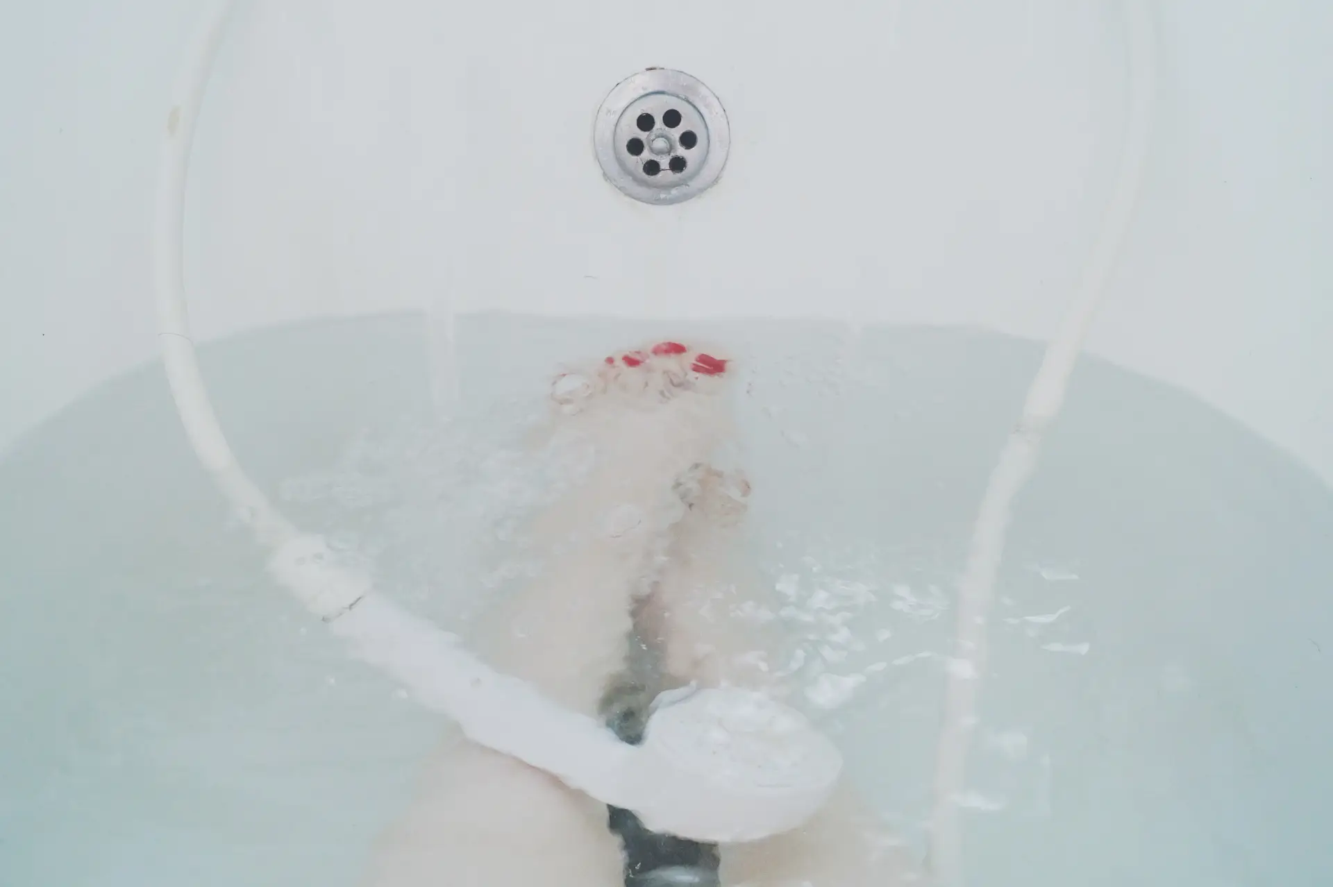 a woman's feet in a bathtub with a handheld shower head