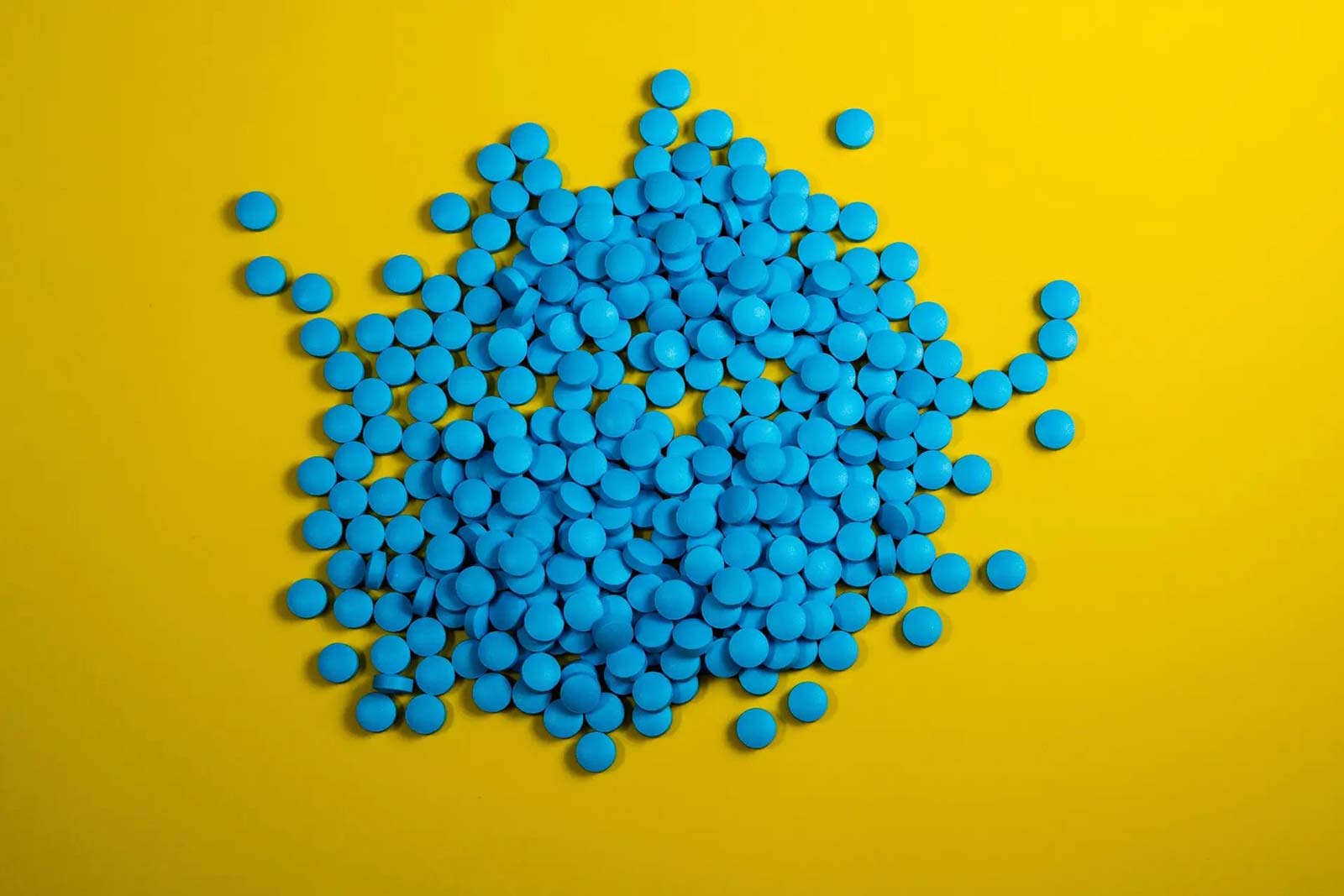 pile of blue pills on a yellow background