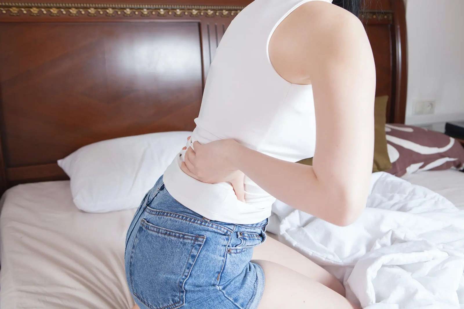 a woman with lower back pain sitting on a bed