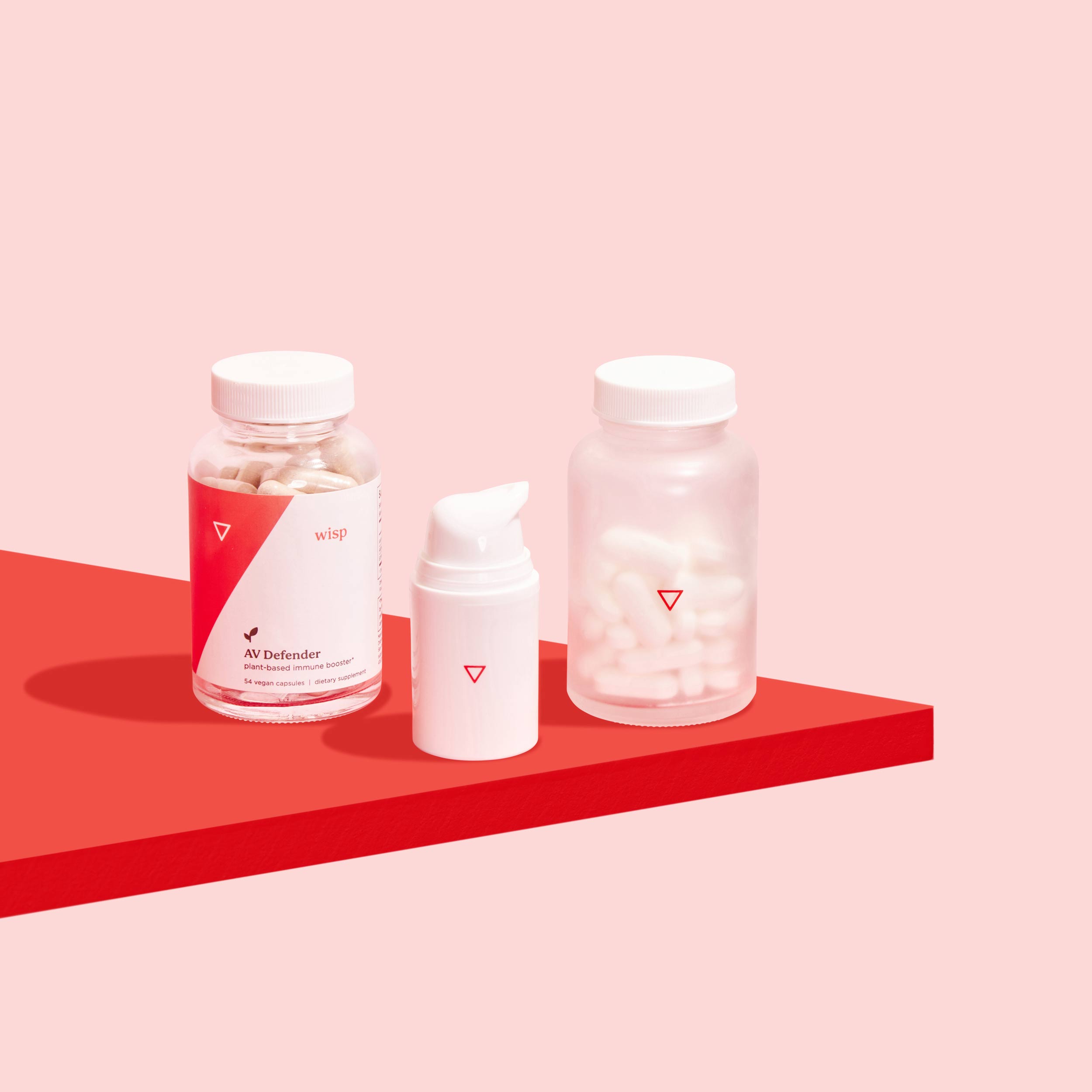 Bottle of AV Defender, bottle of acyclovir cream, and bottle of valacyclovir tablets to treat and prevent oral and genital herpes outbreaks on a red surface, on a pink background