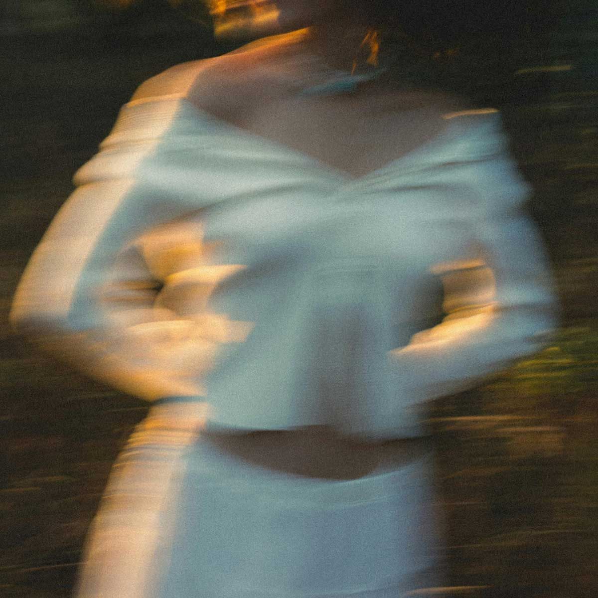 A woman wearing white clothing is moving outdoors with motion blur
