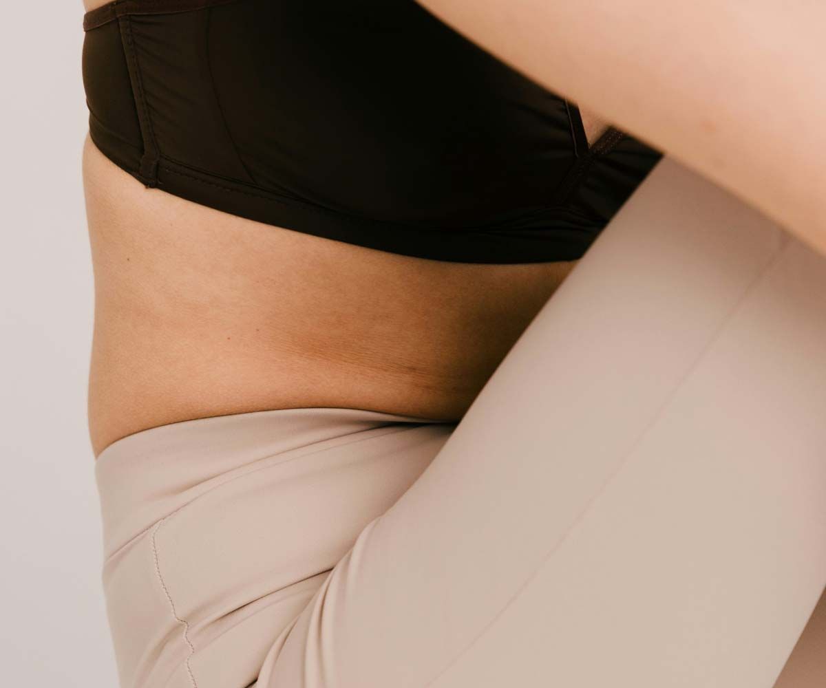 A close up of a woman's midsection with her sitting down with fitness clothing on