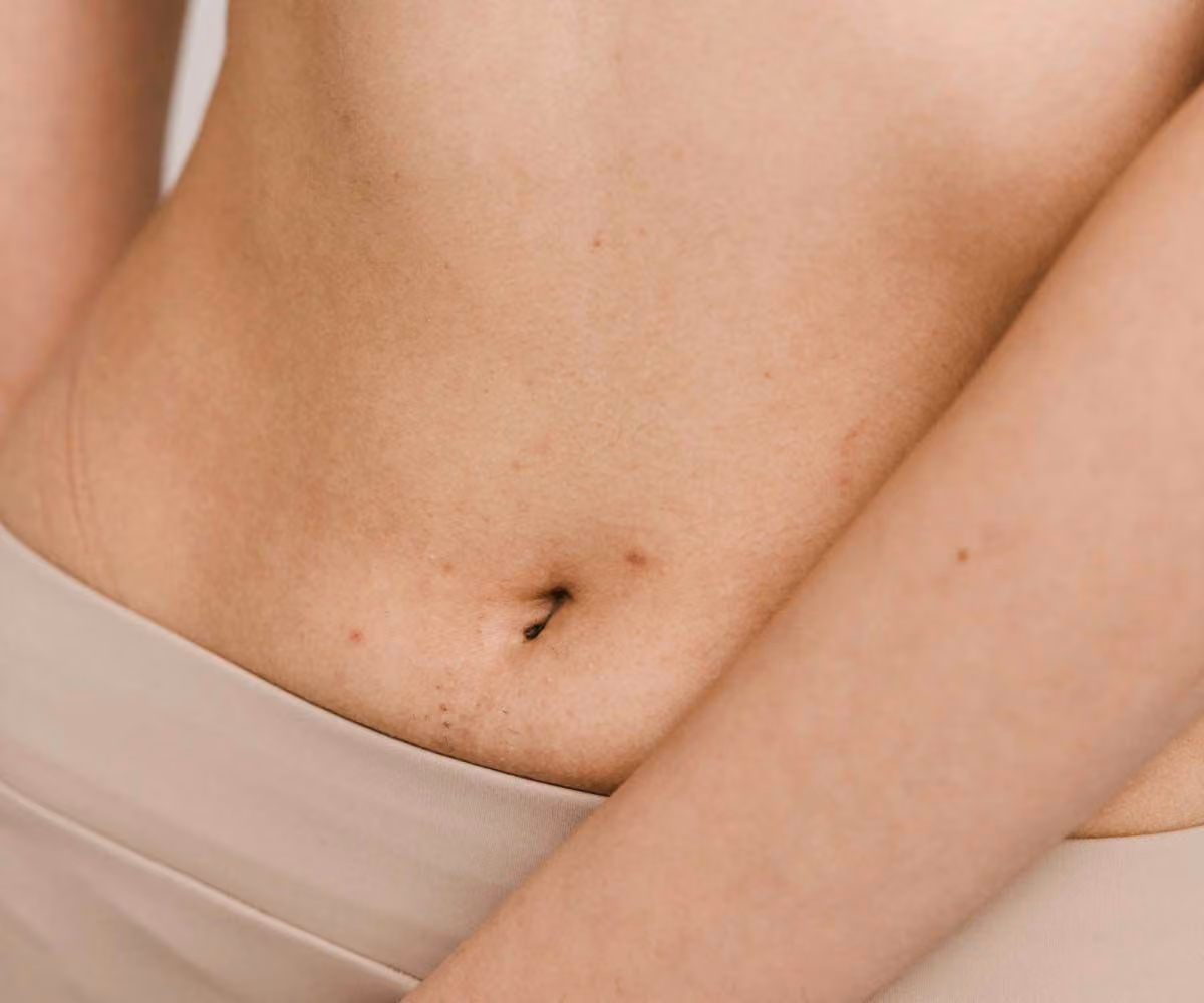 A close up of a woman's midsection with a cream background