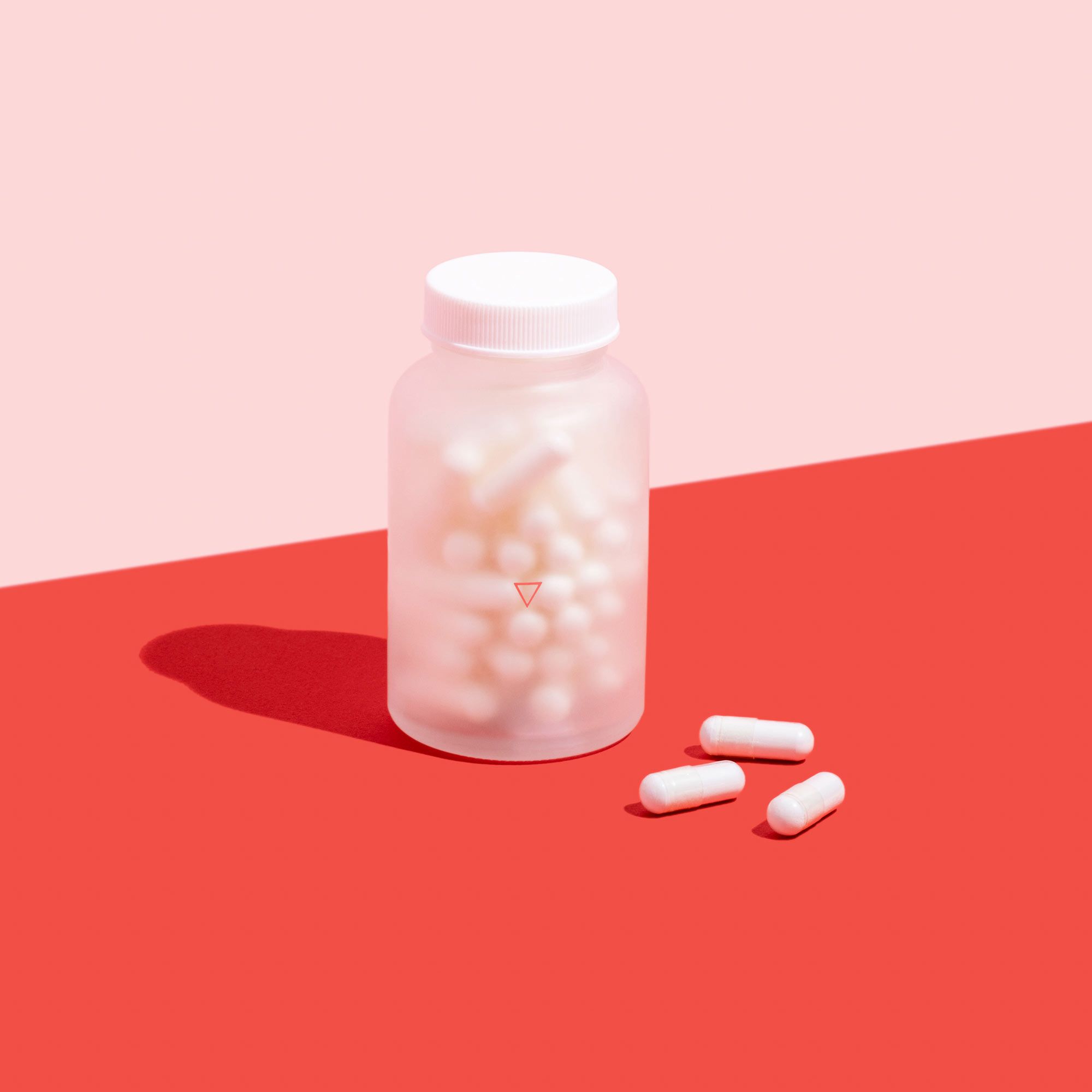 Jar of Lysine capsules to treat oral and genital herpes on a pink background and red surface
