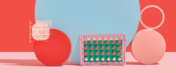 The birth control patch, ring, and pill are balanced on colorful abstract shapes on a pink surface with a red background