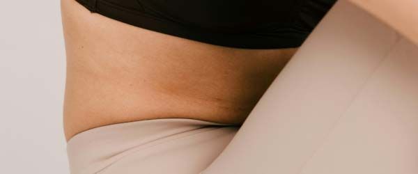 A close up of a woman's midsection wearing black and tan workout clothing