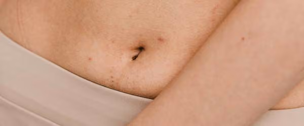 A close up of a woman's midsection with a cream background