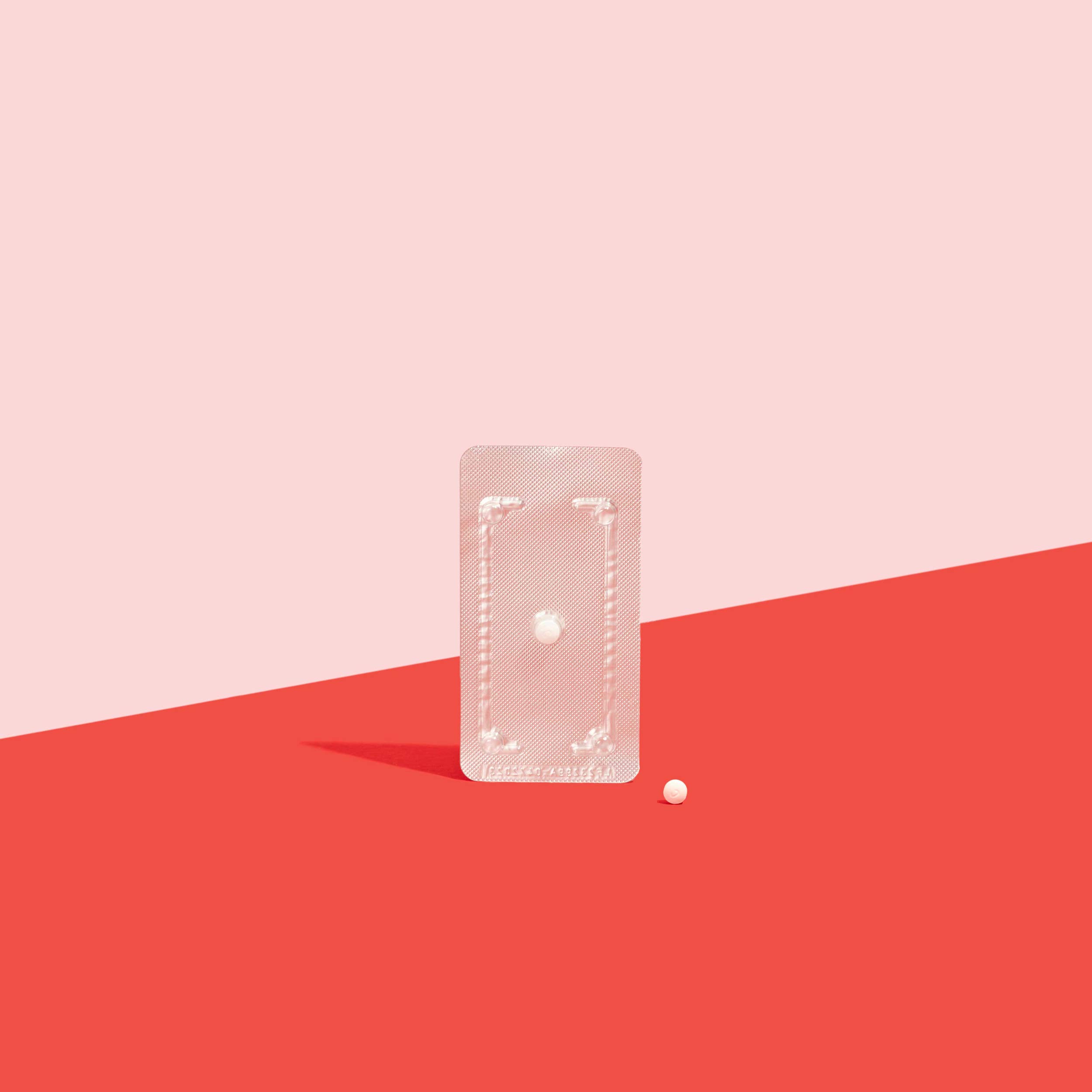 Plan B emergency contraception in foil packet to prevent pregnancy on a red surface, on a pink background