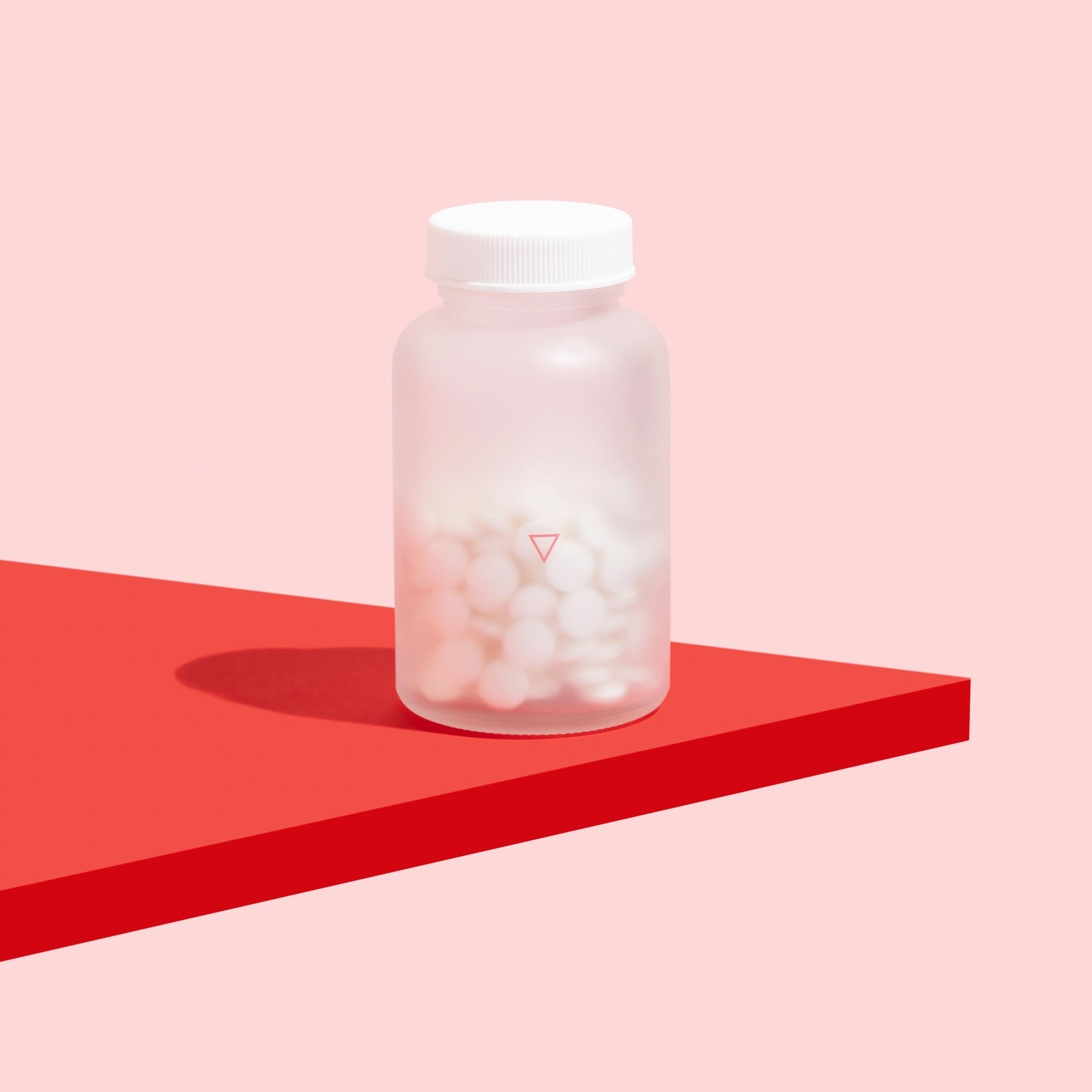 Bottle of probiotics for online reproductive health on red surface, on pink background