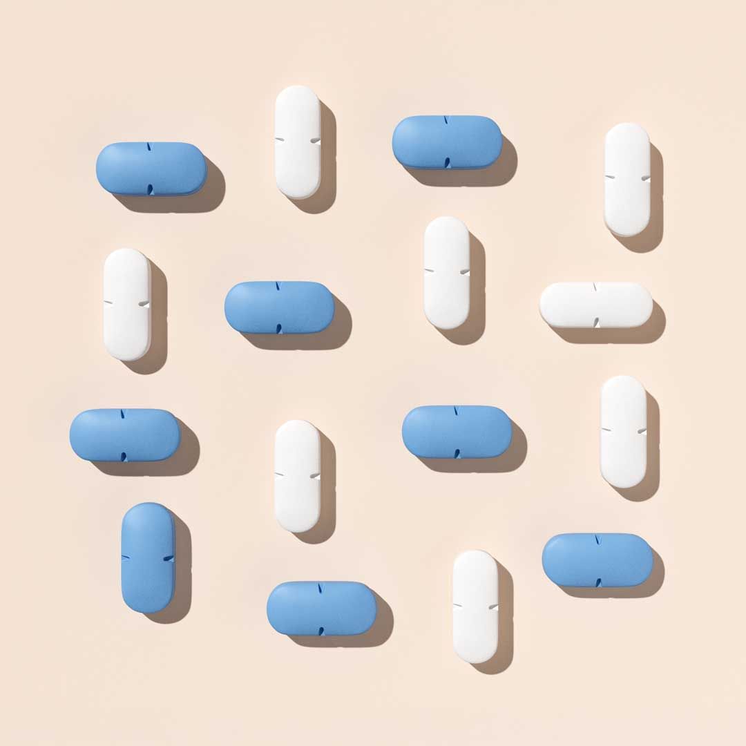 Blue and white pills arranged in a pattern on a cream surface