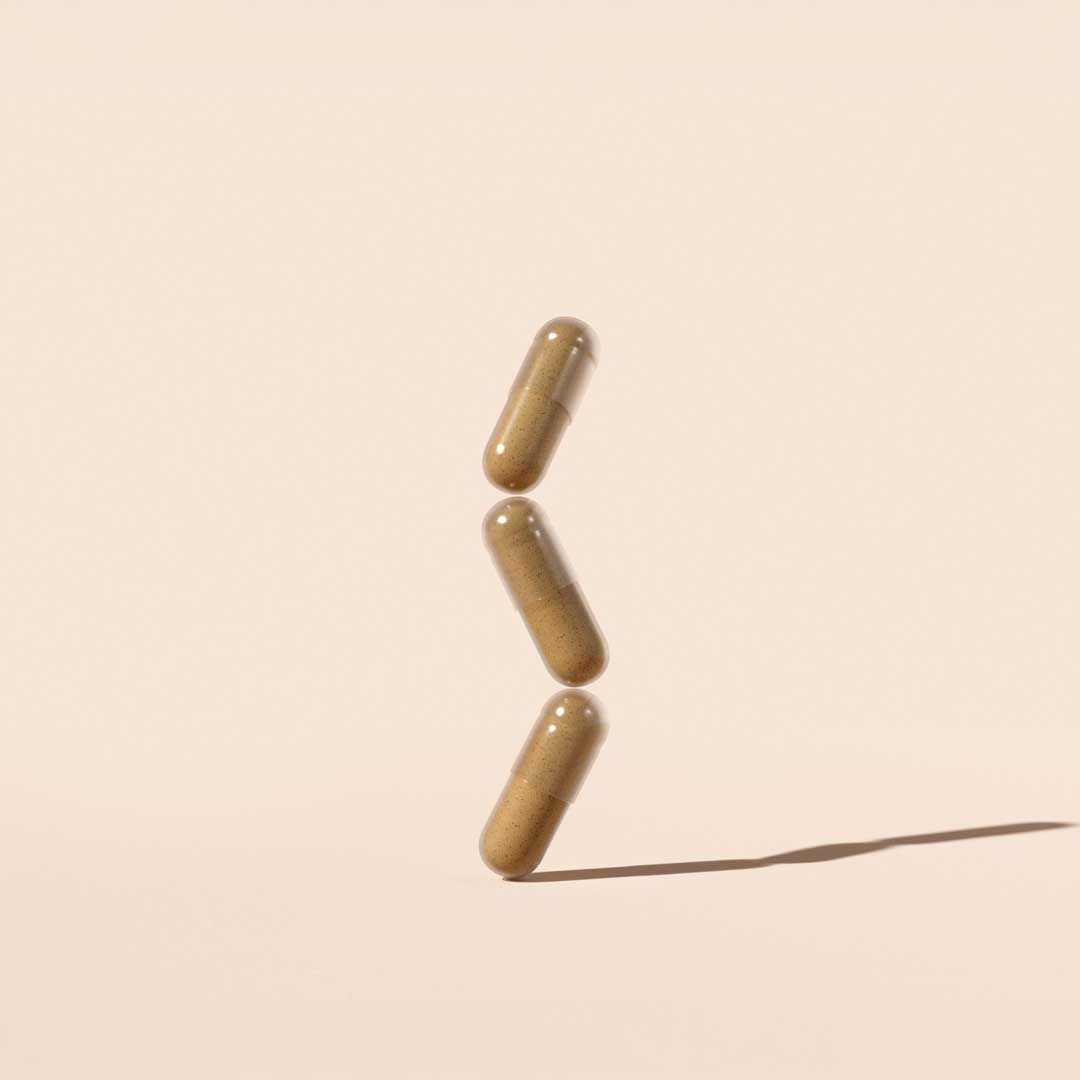 Stacked AV Defender pills on a cream surface